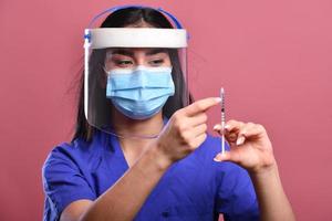 femmina medico indossare viso scudo e ppe completo da uomo per coronavirus scoppio Tenere vaccino e covid test. concetto di covid-19 foto