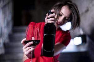 femmina alla moda modello Tenere bicchiere e bottiglia di vino. donna bere vino. foto