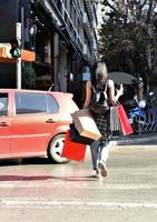 bellissimo donna a piedi su il strada con shopping borse. di moda femmina modello nel il città Tenere shopping borse. foto