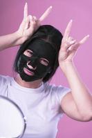 giovane bellissimo donna in posa con nero cosmetico maschera su sua viso foto