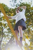 giovane uomo equilibratura e salto su slackline. uomo a passeggio, salto e equilibratura su corda nel parco. foto