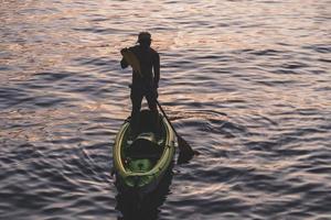 bello sportivo uomo è kayak su tramonto foto