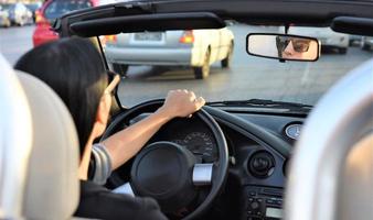 contento bellissimo biondo giovane donna guida un' gli sport auto nel il città foto