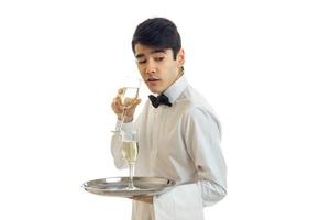affascinante Cameriere nel un' bianca camicia Tenere un' bicchiere di vino e meraviglie foto
