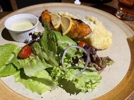 affumicato grigliato salmone pesce servito con insalata e miscuglio patate con limoni foto