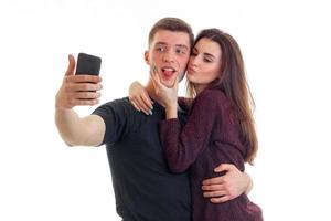 bellissimo ragazza baci su il guancia di un' giovane attraente tipo e lui fa selfi su Telefono foto