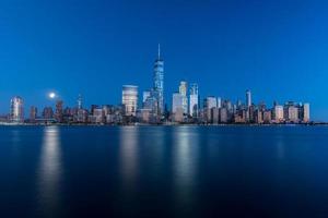 nuovo York orizzonte come visto attraverso il hudson fiume nel nuovo maglia a crepuscolo con il super Luna nel il sfondo. foto