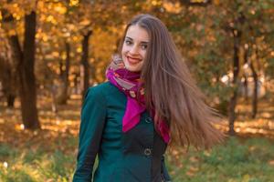 ragazza con dritto lungo capelli sta nel autunno parco e sorrisi foto