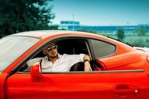 elegante uomo nel occhiali da sole nel rosso sport auto foto