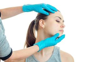 cosmetologo controlli mani nel guanti viso di un' giovane donna foto