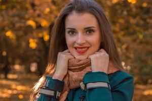 affascinante giovane ragazza con rosso rossetto su labbra Tenere mani e sorridente sciarpa foto