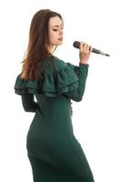 giovane carino ragazza con microfono nel mani nel verde vestito foto