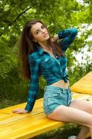 sottile bellissimo ragazza nel plaid camicia si siede su un' panchina foto