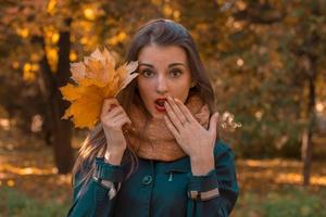 giovane ragazza si chiude sua bocca e mano detiene vicino persona mazzo le foglie avvicinamento foto