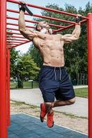 muscolare uomo fare pull-up su orizzontale bar foto