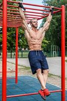 muscolare uomo fare pull-up su orizzontale bar foto