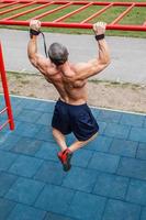 muscolare uomo fare pull-up su orizzontale bar foto