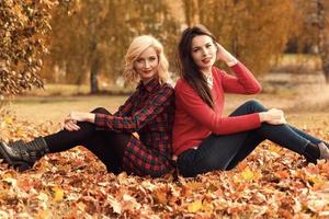 Due bellissimo ragazze amici avendo divertimento nel autunno parco foto