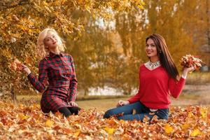 Due bellissimo ragazze amici avendo divertimento nel autunno parco foto