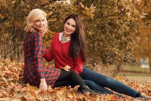 Due bellissimo ragazze amici avendo divertimento nel autunno parco foto