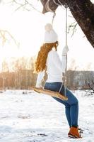 contento ragazza su corda swing a soleggiato inverno giorno foto