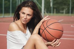 giovane sexy donna con su un' pallacanestro terreno di gioco foto