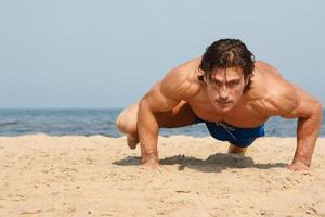 muscolare uomo durante il suo allenarsi su il spiaggia foto