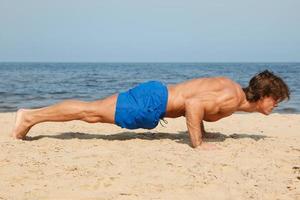 muscolare uomo durante il suo allenarsi su il spiaggia foto