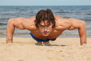 muscolare uomo durante il suo allenarsi su il spiaggia foto