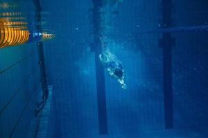 nuotatore donna subacqueo durante sua allenarsi nel il piscina foto