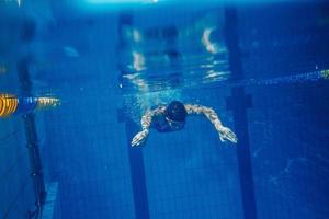 nuotatore donna subacqueo durante sua allenarsi nel il piscina foto