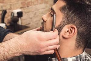 barbiere Lavorando con dritto rasoio per rasatura barba foto