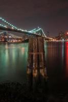 primo piano del ponte di Brooklyn sopra East River di notte a New York City Manhattan con le luci e le riflessioni. foto