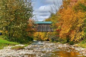 grist mulino coperto ponte nel Cambridge, Vermont durante autunno fogliame. foto