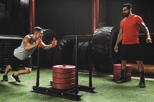 forte sportivo durante slitta spingere esercizio nel attraversare formazione Palestra foto