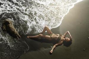 sexy donna con bellissimo corpo è dire bugie su il spiaggia foto