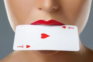 donna con rosso labbra e asso carta nel sua bocca foto
