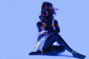 modello nel Immagine di nativo americano con neon trucco, quale fatto di fluorescente dipingere nel ultravioletto luce. foto
