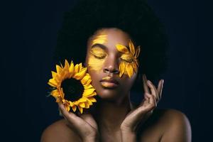 africano donna con un' girasole e creativo trucco su sua viso foto