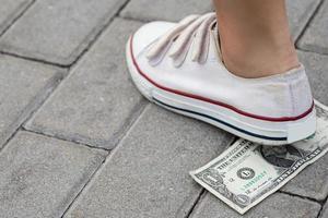 femmina piede e uno dollaro banconota su il terra foto