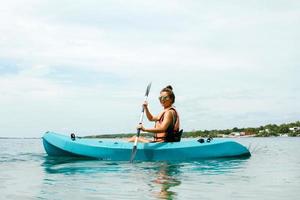 contento giovane donna kayak su il lago foto