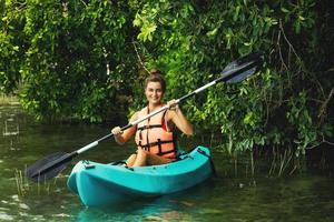 contento giovane donna kayak su il lago foto