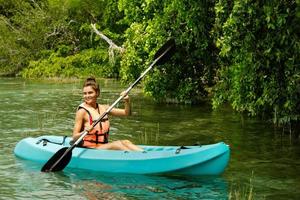 contento giovane donna kayak su il lago foto