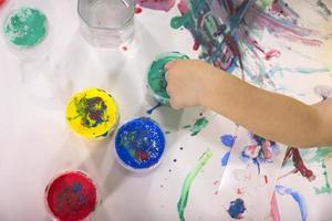 il bambino tuffi il suo dito in acquerello dipingere anziché di un' spazzola per disegno su carta. bambini creatività. foto