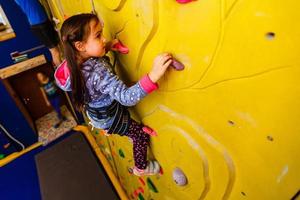 poco ragazza arrampicata un' roccia parete interno. foto