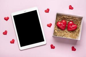 digitale tavoletta per sceglie i regali, fa Acquista, Busta, rosso cuori su rosa tavolo superiore Visualizza piatto posare vacanza shopping elenco, contento San Valentino giorno, festa, in linea negozio concetto finto su foto