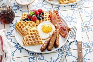 prima colazione tavolo con cialde. fritte uovo, Bacon e salsiccia foto