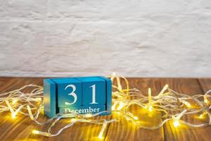 di legno calendario con 31 dicembre parola su raggiante ghirlanda sfondo, nuovo anno vacanza foto
