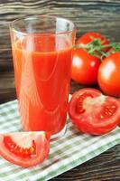 succo di pomodoro e pomodori freschi sulla tavola di legno foto