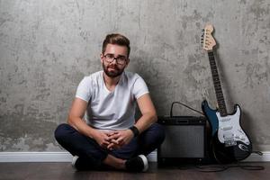 elegante barbuto tipo con chitarra contro calcestruzzo parete foto